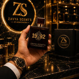 Hand holding a Zavya Scent's perfume bottle with brand logo in the background